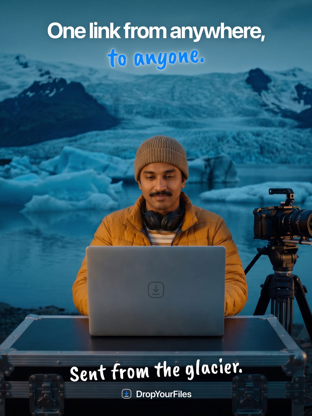 A man in a yellow jacket at a laptop beside a camera on a tripod, in front of a glacier. The headline reads “One link from anywhere, to anyone.” and the line at the foot, “Sent from the glacier.”