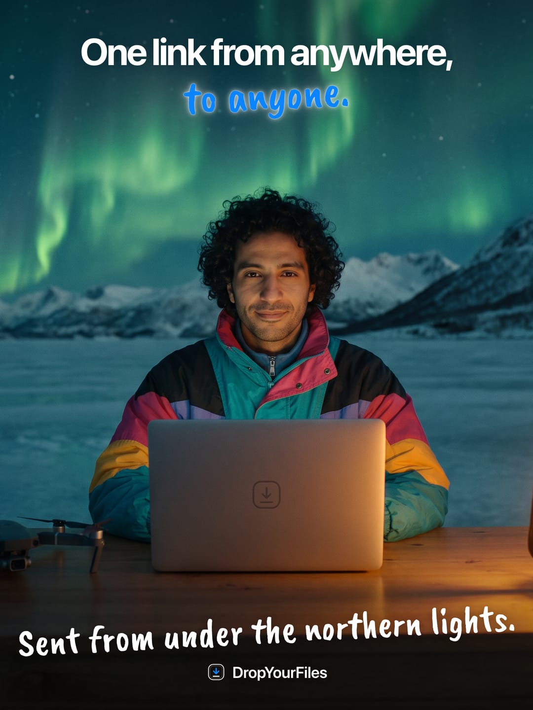 A man in a bright windbreaker at a laptop under the northern lights. The headline reads “One link from anywhere, to anyone.” and the line at the foot, “Sent from under the northern lights.”