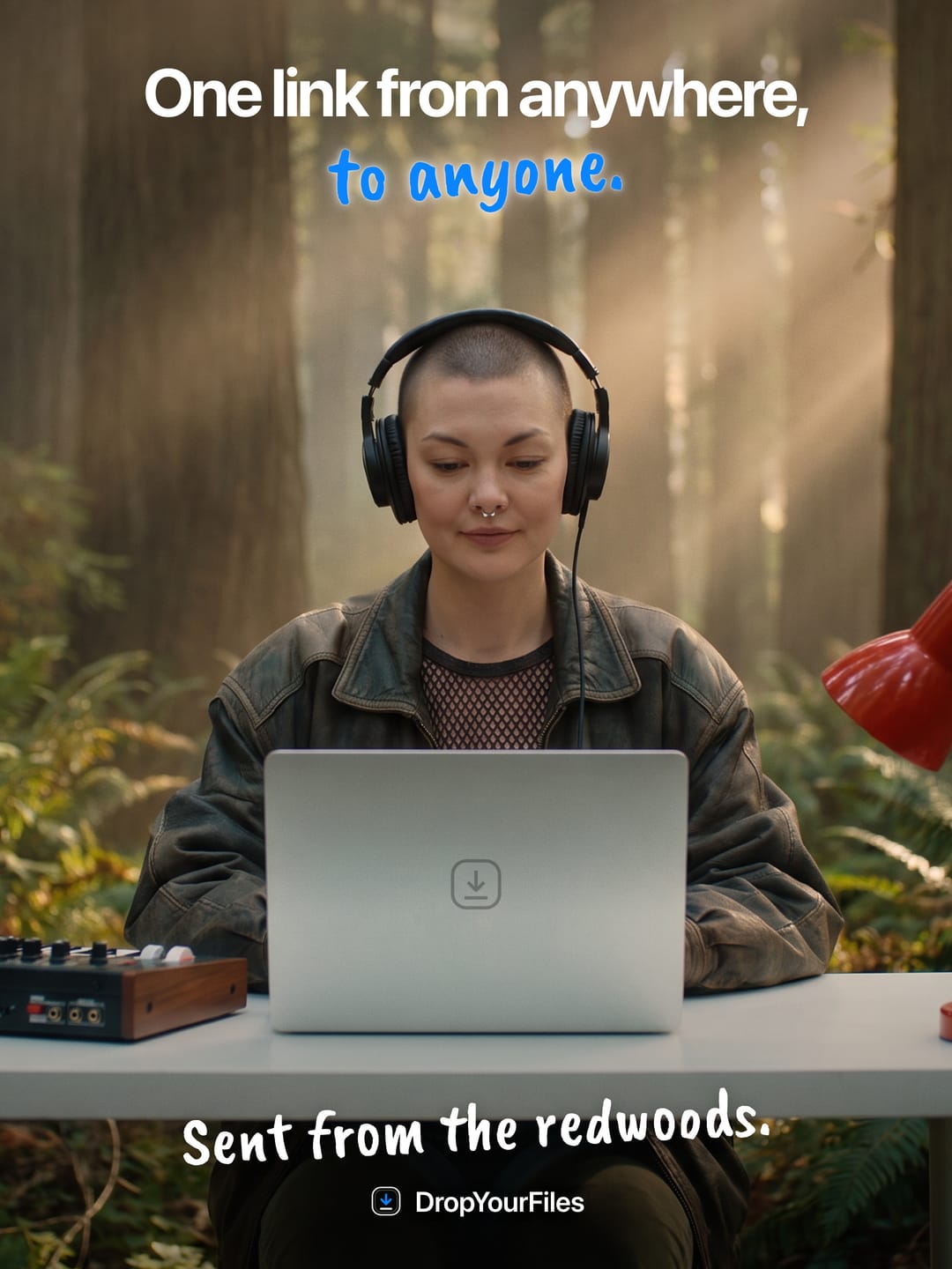 A woman in headphones at a laptop on a desk in a redwood forest. The headline reads “One link from anywhere, to anyone.” and the line at the foot, “Sent from the redwoods.”