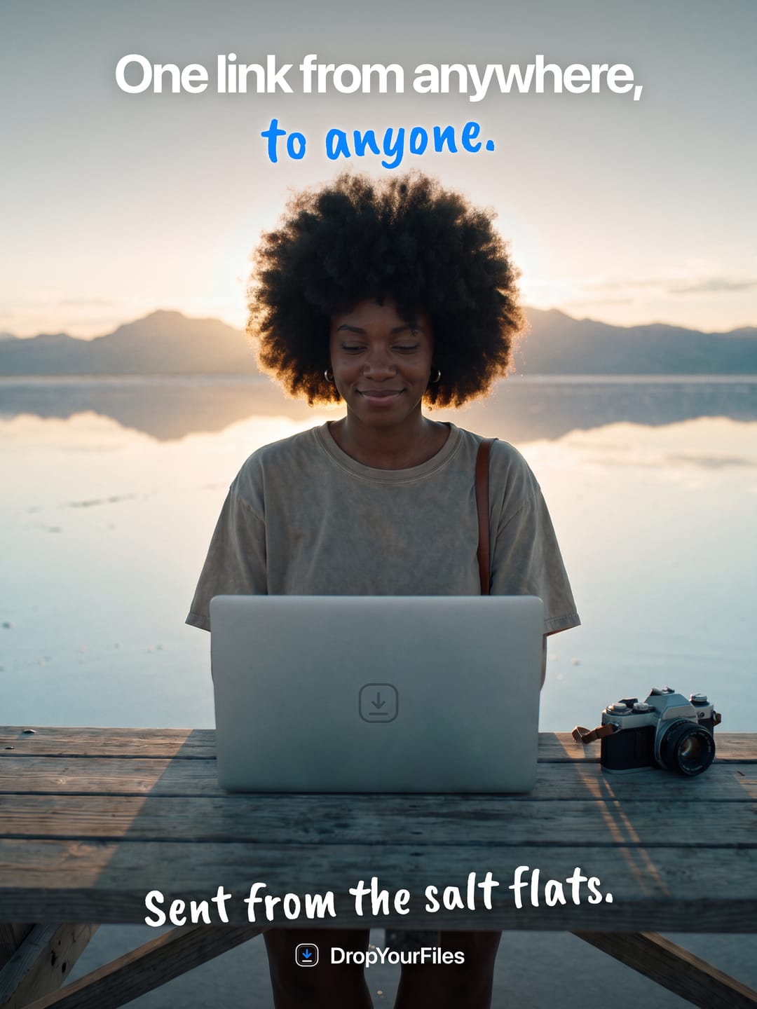 A woman at a laptop on a desk set out on the salt flats at sunrise. The headline reads “One link from anywhere, to anyone.” and the line at the foot, “Sent from the salt flats.”